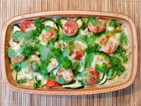Überbackener Gemüseauflauf in Auflaufform mit Zucchini, Tomaten und Petersilie