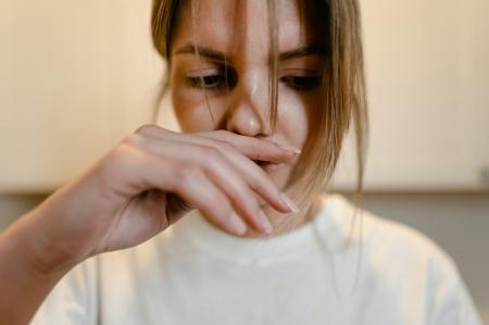 Frau, die sich die Hand vor die Nase hält.